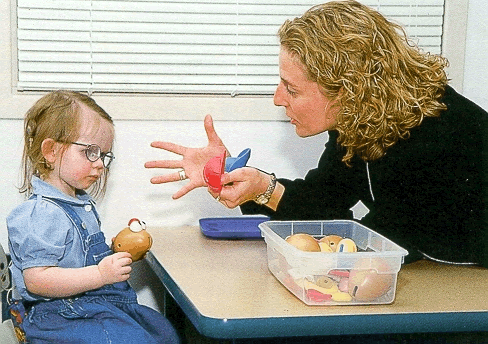 Speech-language professional working with a child during an interactive therapy activity